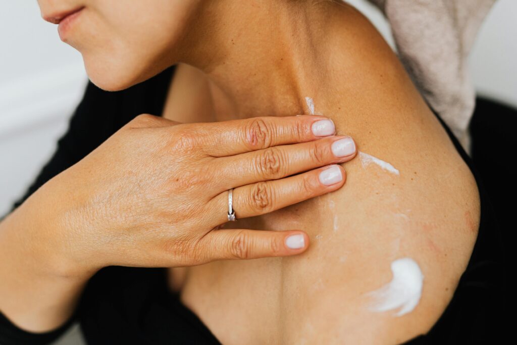 Mujer aplicando crema en el cuello y el escote durante su rutina de cuidado facial